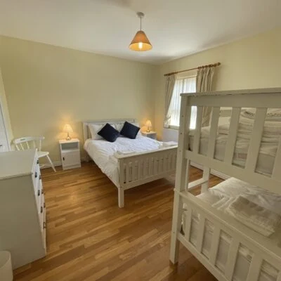 Redory House - Spacious family room which white wooden double bed and bunk beds,  Bedside cabinet, chair and chest of drawers in matching white wood.