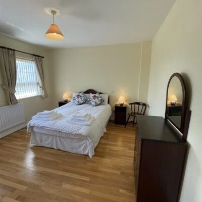 Redory House - Double bed with window on left hand side of the room. Bedside cabinet and chair on right hand side of the bed. Dressing table with mirror in the fore.