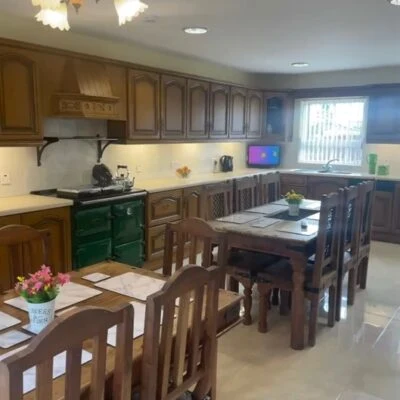 Redory House - Large spacious fitted kitchen with oil fired stove.  2 long rectangular tables tables and chairs to seat 12 people. Smart TV sitting on workbench besi