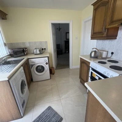Redory House - Utility room showing washing machine, tumble dryer, cooker, toaster, kettle, waffle and toastie maker.