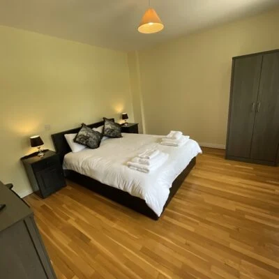 Redory House - Double bedroom with hard floor wooden floor. Double bed dressed in white linen, bedside cabinets on both sides of the bed. Wardrobe and side of dressi